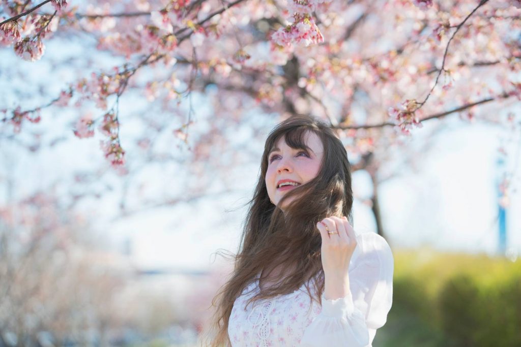 woman looking at cherry blossom 